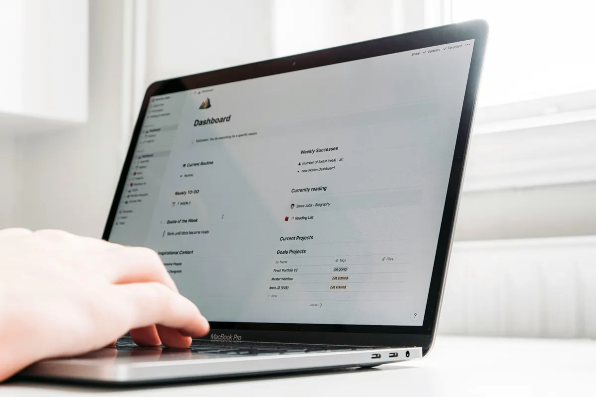Indépendant travaillant sur un MacBook Pro affichant un dashboard type Notion utilisé comme exemple de CRM